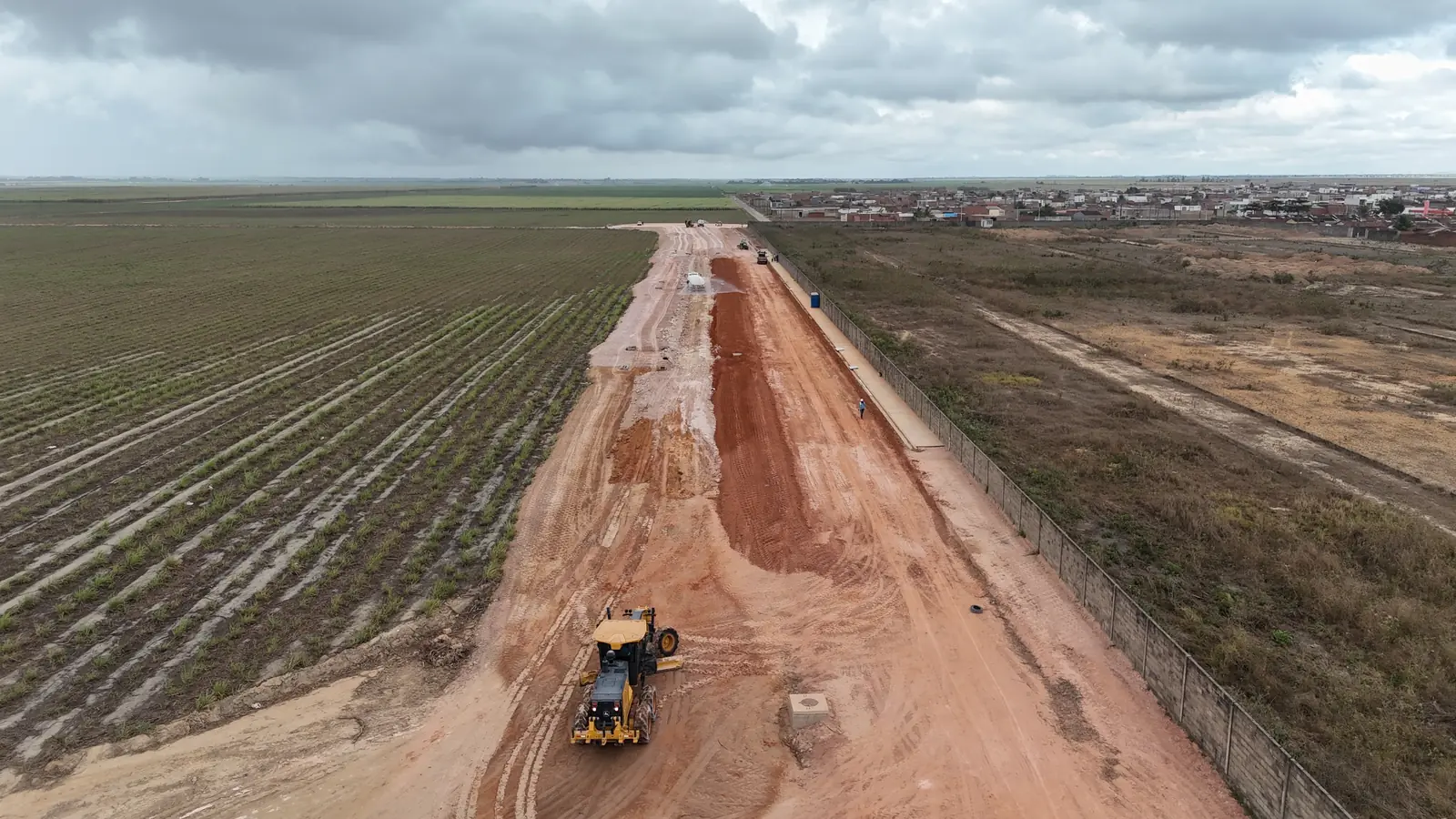 Motoniveladora abrindo o leito da Avenida do Futuro entre plantações