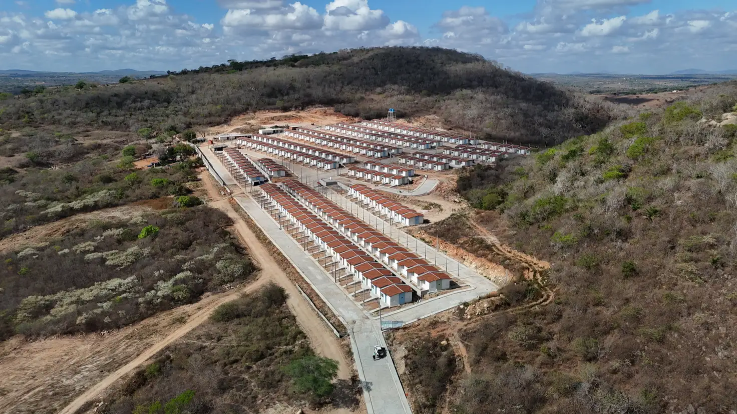 Vista aérea do conjunto habitacional e do acesso, cercados pela vegetação