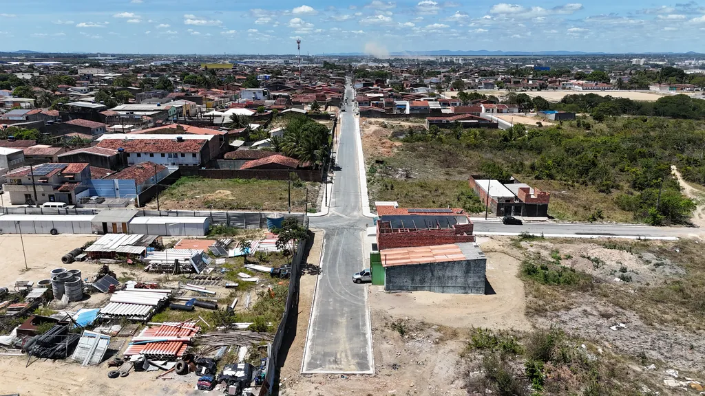 Rua pavimentada em Santa Lúcia vista do alto, com casas e terrenos dos lados